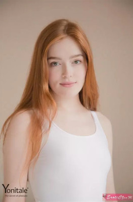 Рыжеволосая молодая красавица в белом боди на кровати